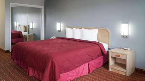 a hotel room with a large bed with a red blanket at Rodeway Inn in Beebe