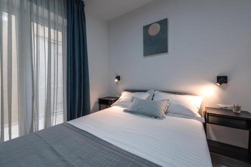 a bedroom with a large white bed and a window at Apartman Festini in Pag
