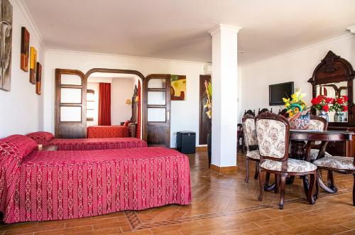 a bedroom with two beds and a table and chairs at Hotel Pozo del Duque in Zahara de los Atunes