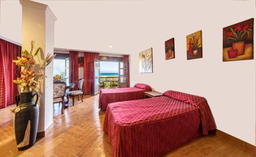 a hotel room with two beds and a table at Hotel Pozo del Duque in Zahara de los Atunes