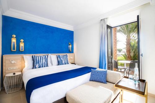 a bedroom with a blue and white bed and a couch at Sol Oasis Marrakech - All Inclusive in Marrakesh