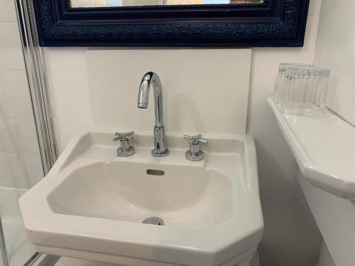 un lavabo blanc dans une salle de bain avec un miroir dans l'établissement La régate Wimereux - vue mer, à Wimereux