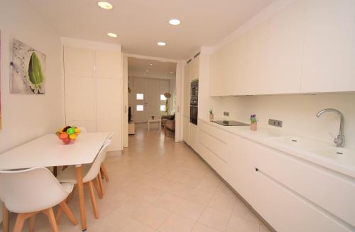 - une cuisine avec des placards blancs, une table et des chaises dans l'établissement Casa Can Salroig 002 by Mallorca Charme, à Muro