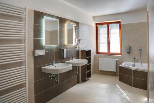 a bathroom with two sinks and a tub and mirrors at Golf&Wellness Resort Alfrédov in Alfrédov