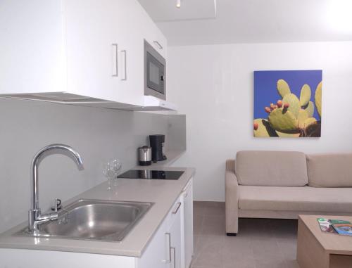 a white kitchen with a sink and a couch at Apartamentos Las Buganvillas Adults Only in Puerto Rico de Gran Canaria