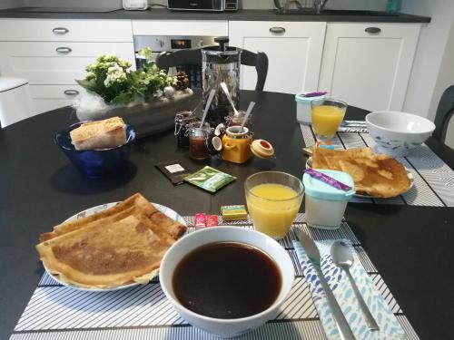 a breakfast table with toast and coffee and orange juice at Chambres d'hôtes cosy avec salle de bain privative - Wifi - cuisine partagée - Parking gratuit in Ploufragan