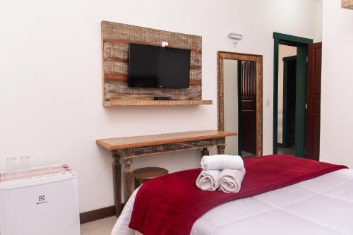um quarto com uma cama e uma televisão na parede em Solar de Amelia em Tiradentes