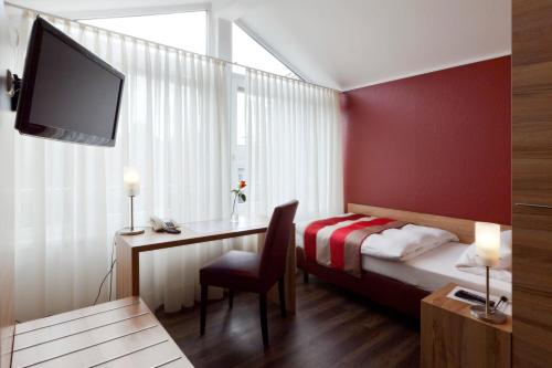 a hotel room with a bed and a desk and a tv at Adolphs Hotel in Cologne