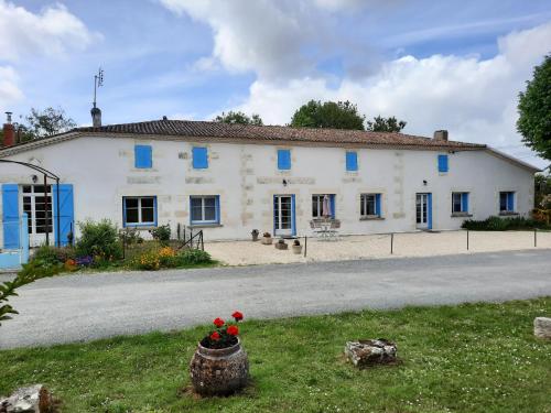 ein weißes Haus mit blauen Rollläden auf einer Straße in der Unterkunft Gîte de La Garenne in Cozes
