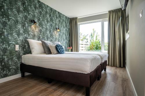 Hotel het Anker van Texel في دي كوكْسدوربْ: غرفة نوم بسرير كبير وورق جدران أخضر