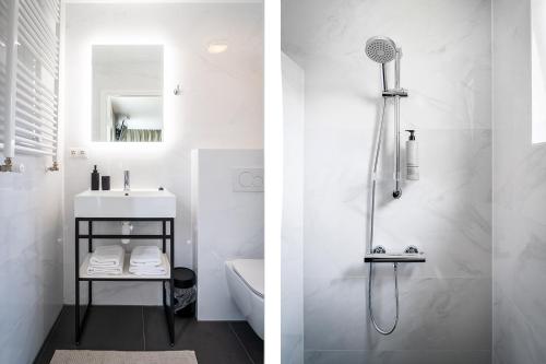 La salle de bains blanche est pourvue d'une douche et d'un lavabo. dans l'établissement Hotel het Anker van Texel, à De Cocksdorp