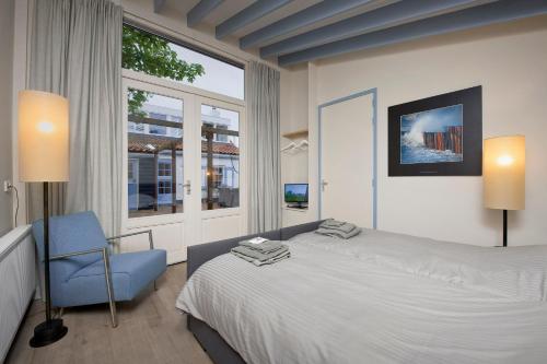 a bedroom with a bed and a blue chair at B&B Zee van Tijd Domburg in Domburg
