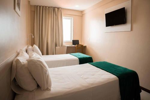 a hotel room with two beds and a television at Green Hotéis in Cabo Frio