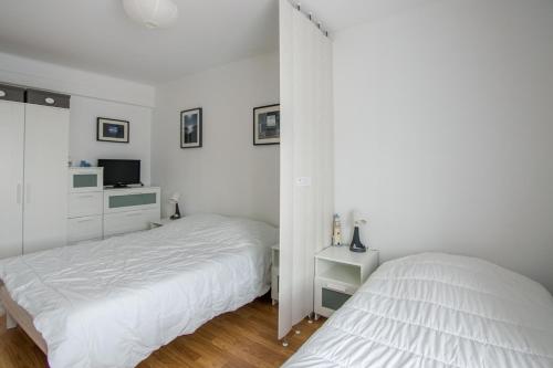 2 bedden in een slaapkamer met witte muren bij Le Sainte Anne in Saint-Malo