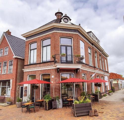 a building with tables and umbrellas in front of it at Boutique Hotel Joure - centrum & haven in Joure