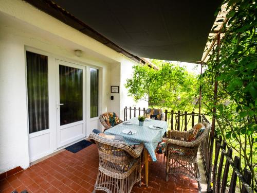 eine Terrasse mit einem Tisch und Stühlen auf einer Veranda in der Unterkunft Liget Holiday Home in Fonyód