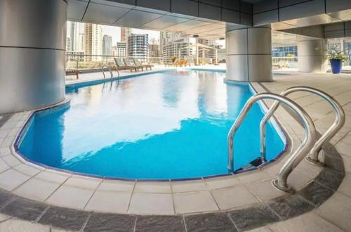 a large pool with blue water in a building at Beautiful Close to Beach Dubai Marina Apartment in Dubai