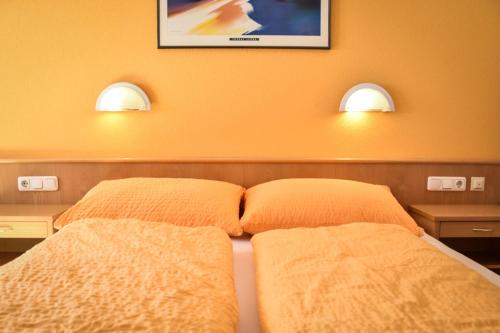 a bedroom with two beds and two lights on the wall at Haus Alpenblick in Schröcken