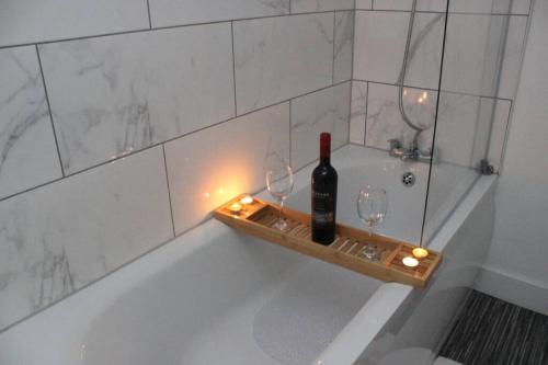 a bath tub with a bottle of wine and two glasses at Newly Refurbished 3 Bed 2.5 Bath House in Staines in Staines