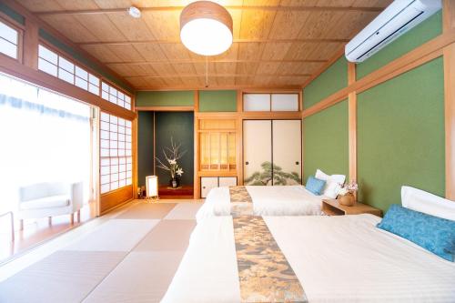 two beds in a room with green walls at Awaji egaosakuie tonouchi in Awaji
