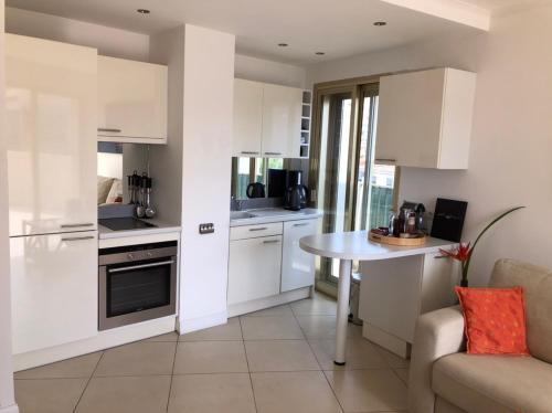 une cuisine avec des armoires blanches, une table et un canapé dans l'établissement Esterel Terrasses, roof top, plage, parking payant, à Cannes
