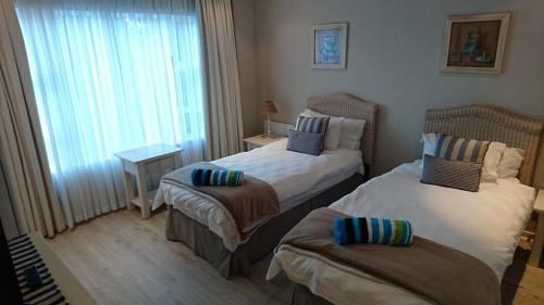 ein Hotelzimmer mit 2 Betten und einem Fenster in der Unterkunft Lodge 93 in Mossel Bay