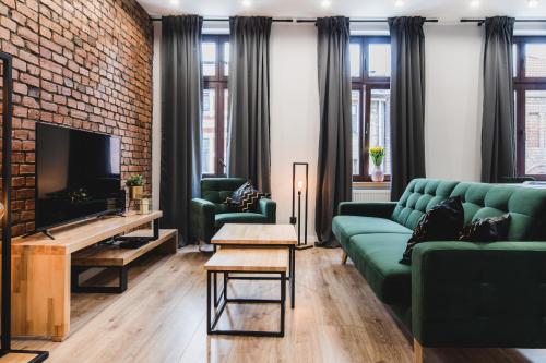 a living room with a green couch and a brick wall at Modern Apartments Toruń 3 in Toruń