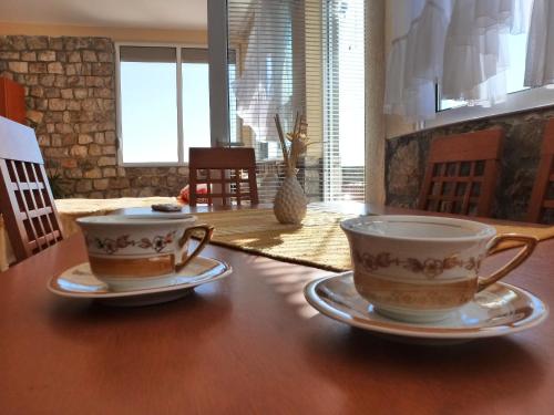 two cups and saucers sitting on a wooden table at Apartments Antigona Old Town in Ulcinj