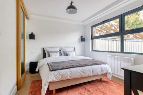 een slaapkamer met een bed en een groot raam bij L' Annexe du Cosmopolitain in Honfleur