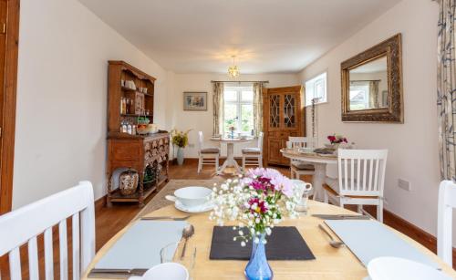 a dining room with a table with flowers in a blue vase at Avalon House B&B in Lyndhurst