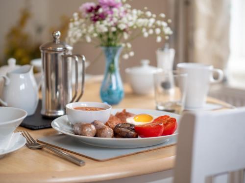 a plate of food on a table with eggs and tomatoes at Avalon House B&B in Lyndhurst