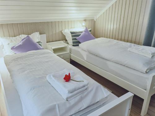 two beds with towels and a red flower on them at BanPim Beachside Lofoten in Ramberg