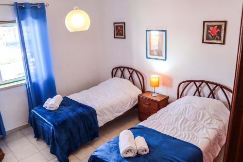 a bedroom with two beds with blue sheets and towels at Apartamento Jardim de Sta Eulália in Albufeira