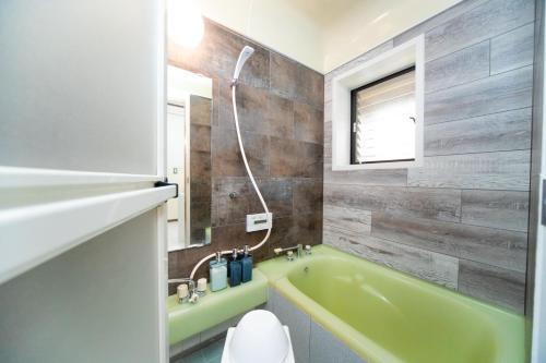 a bathroom with a green bath tub next to a toilet at Awaji egaosakuie tonouchi in Awaji