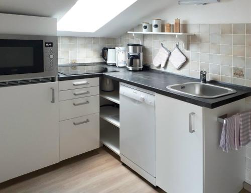 a white kitchen with a sink and a microwave at Ferienwohnung Aigner in Bischofswiesen