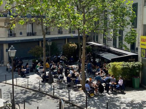 a group of people sitting at tables in a courtyard at Hôtel Edgar & Achille in Paris