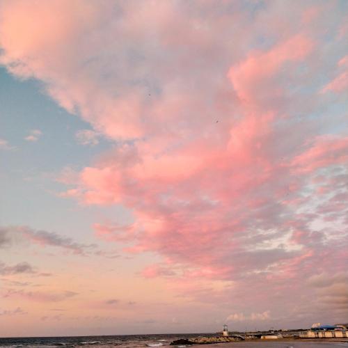 a sky filled with pink clouds over the ocean at B&B Mariupol in Trapani