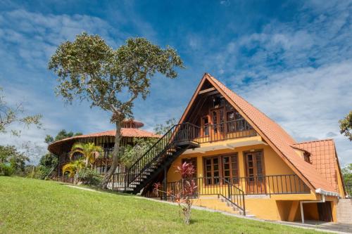a house with a balcony and a tree at San Agustin Internacional Hotel in San Agustín