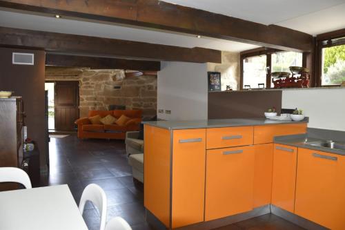 eine Küche mit orangefarbenen Schränken und ein Wohnzimmer in der Unterkunft Ribeira sacra ourense in Ourense