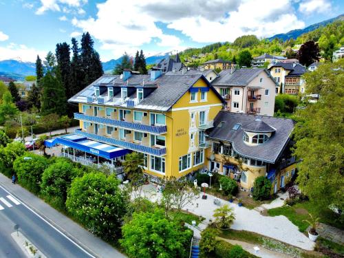 an aerial view of a large yellow house at Hotel Nikolasch in Millstatt