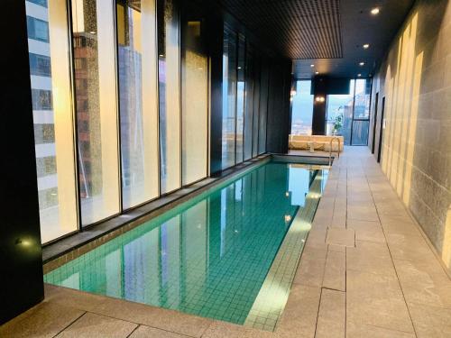 a swimming pool in a building with windows at Melbourne CBD Empire Apartment in Melbourne