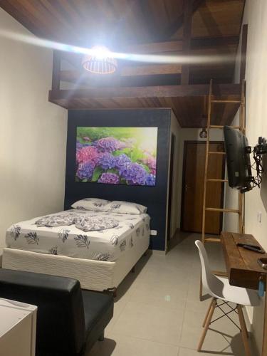 a bedroom with a bed with a painting on the wall at Chales em Salesopolis - Recanto da Barra in Salesópolis