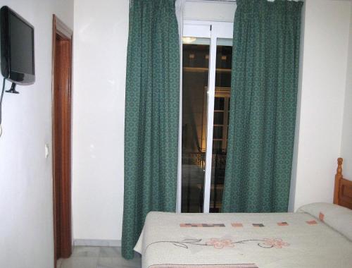 1 dormitorio con cortinas verdes, 1 cama y ventana en Veracruz, en Granada