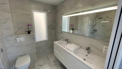 een witte badkamer met een wastafel, een bad en een spiegel bij LES VILLAS DU DOMAINE NAPOLEON CORSICA vue mer et piscine in Pietrosella