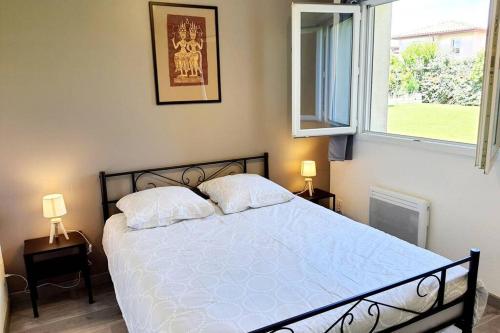 una camera da letto con un letto con due cuscini e una finestra di Charmant appartement avec terrasse et jardin au calme Proche Bus Métro a Tolosa