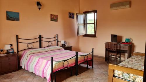a bedroom with a bed and a desk and a window at B&B Nuraximannu in Santadi
