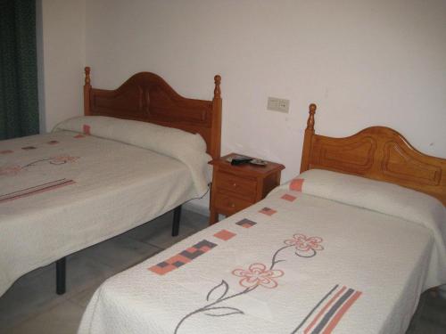 a bedroom with two beds with white sheets and flowers at Veracruz in Granada