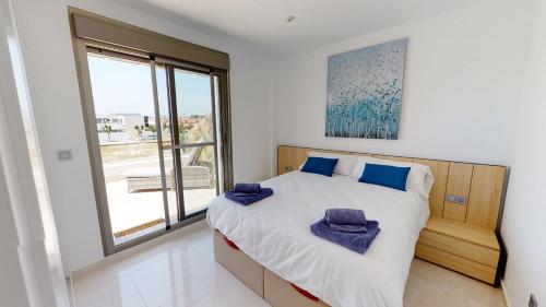 a bedroom with a bed with blue pillows on it at Villa Mercurio - A Murcia Holiday Rentals Property in Los Alcázares
