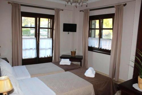 a hotel room with two beds and two windows at Guesthouse Vavitsas in Kalabaka