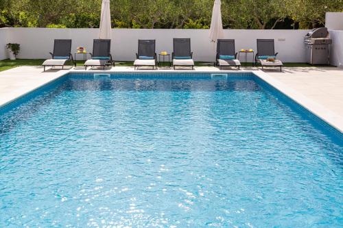 une piscine avec des chaises longues et une piscine dans l'établissement Villa Corcovado, à Vodice